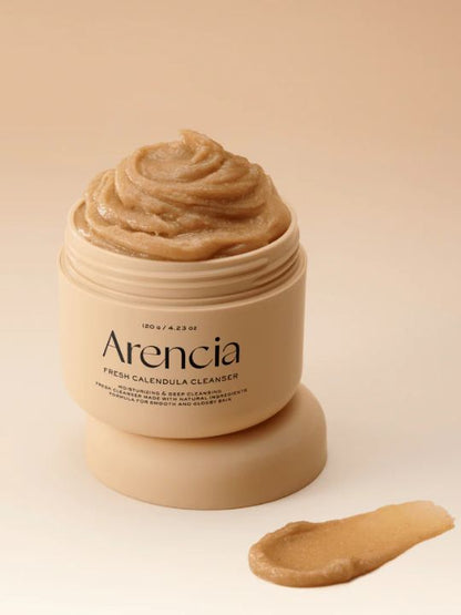 Jar of Arencia Calendula Rice Mochi Cleanser with a swatch on a beige background
