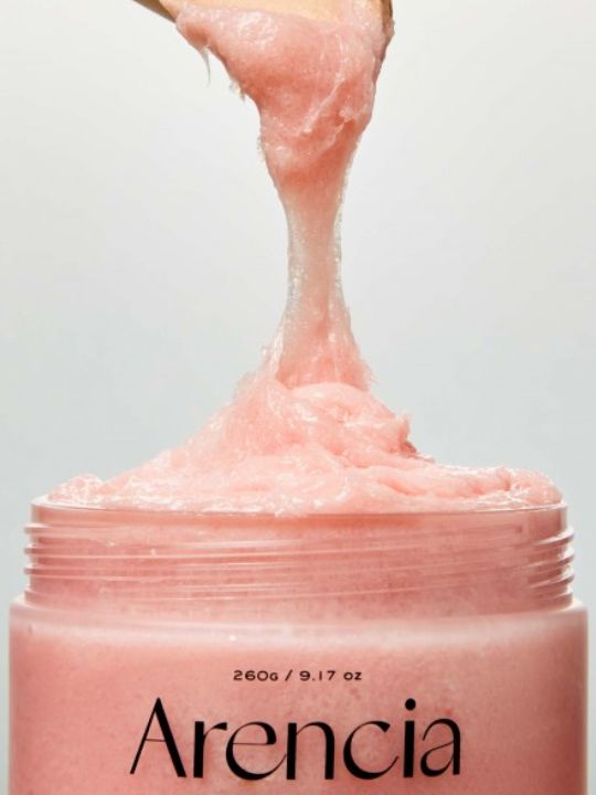 A close-up of open jar of Arencia Cloud Body and Scalp Scrub Lavender & Pear. The pink creamy product is shown stretching upward against a clean light background.