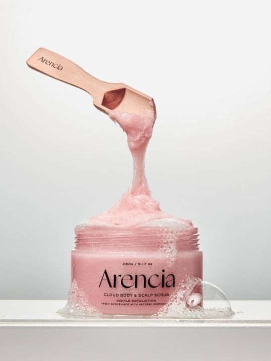 Open jar of Arencia Cloud Body & Scalp Scrub Pear & Lavender with a floating wooden spatula on a light grey background