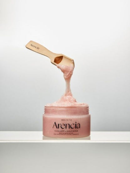 Open jar of Arencia Cloud Body & Scalp Scrub Pear & Lavender with a floating wooden spatula on a light grey background