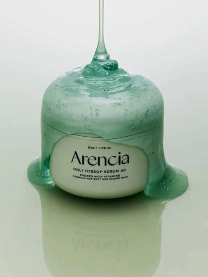 Jar of Arencia Holy Hyssop Serum 30 with green jelly serum being poured on top, on a light green background.
