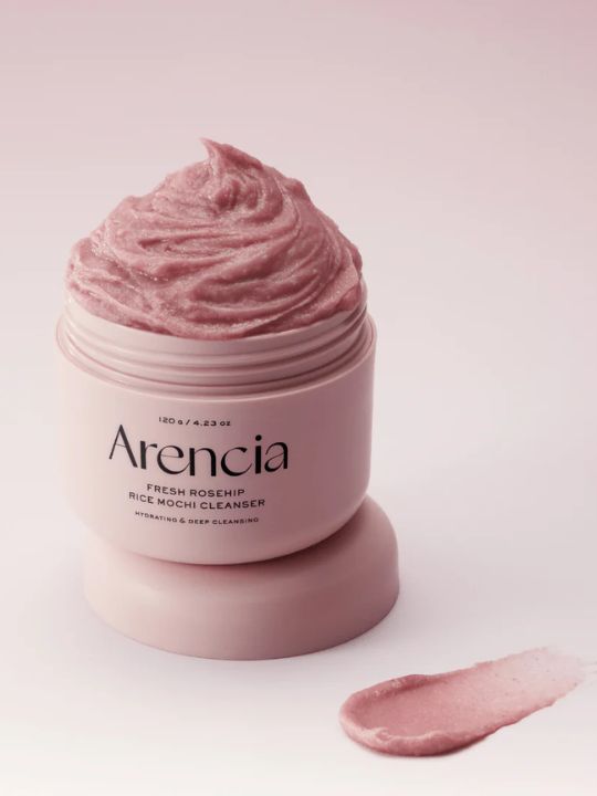 Open jar of Arencia Rosehip Rice Mochi Cleanser with swatch on a light pink background