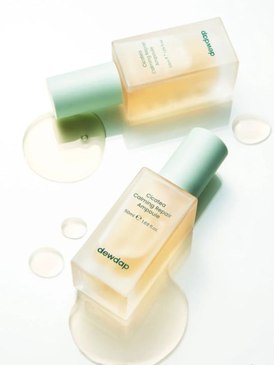 2 bottles of Dewdap Cicatea Calming Repair Ampoule on a white background with puddles of liquid