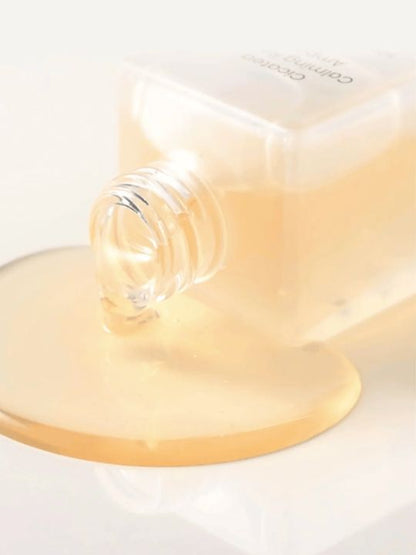 Close up of Dewdap Cicatea Calming Repair Ampoule tipped over with serum pouring out, on a white surface