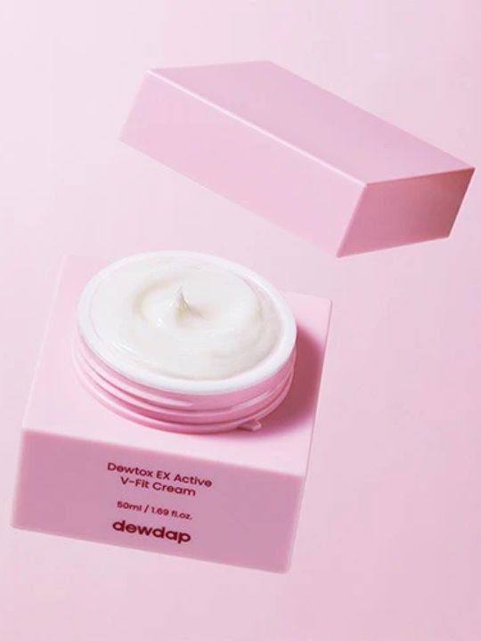 Open jar of Dewdap's Dewtox EX Active V-Fit Cream with its lid hovering above, on a light pink background