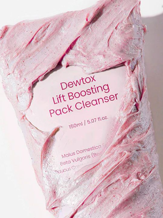 Close up of Dewdap's Dewtox Lift Boosting Pack Cleanser tube covered in pink cream, against a light pink background
