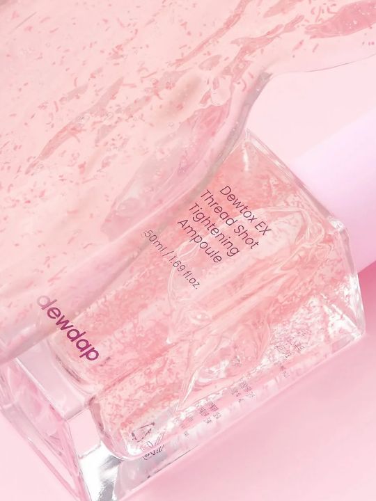 Dewdap's Dewtox Thread Shot Tightening Ampoule on a light pink background with liquid elements surrounding the bottle