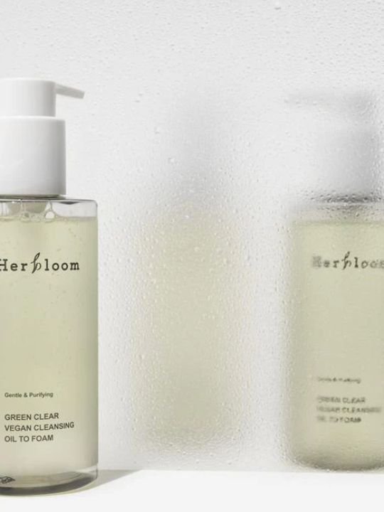 Two bottles of Herbloom Green Clear Vegan Cleansing Oil to Foam on a white background with condensation and water droplets