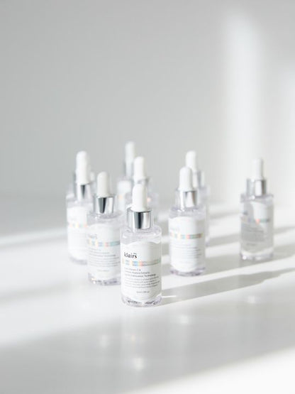 Set of Klairs Freshly Juiced Vitamin Drop bottles with shadows on a light grey surface and background