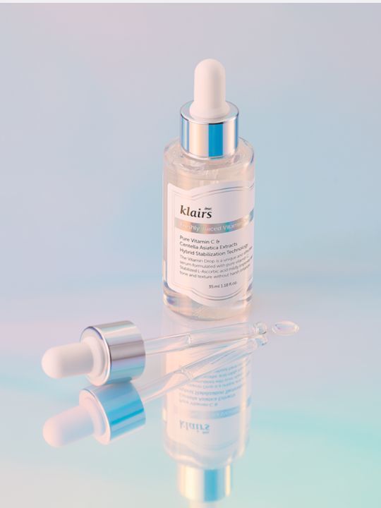 Klairs Freshly Juiced Vitamin Drop bottle with dropper on a light blue gradient, reflective background