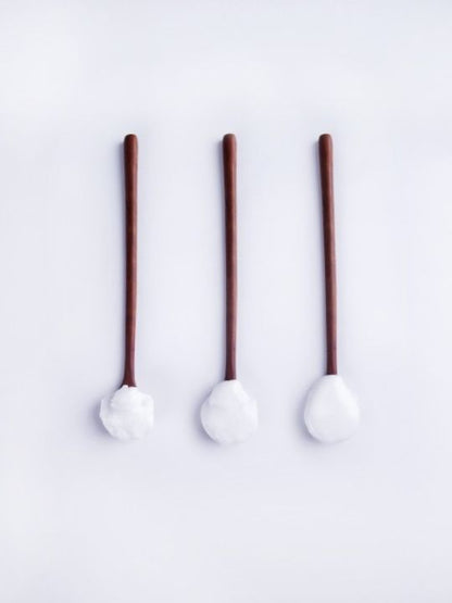 Three spoons with brown handles and white cream on a white background