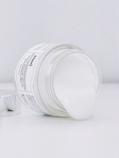 Klairs Freshly Juiced Vitamin E Mask without a lid and tipped over with cream coming out on a white surface and background