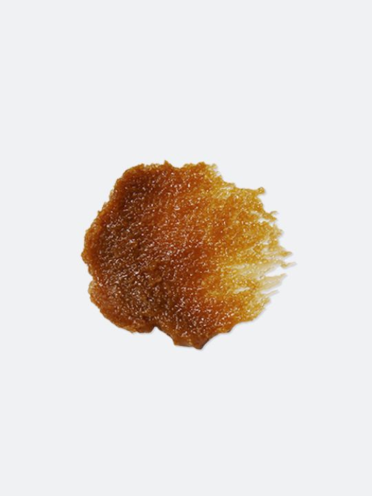 Close-up of a clump of brown facial scrub on a white background