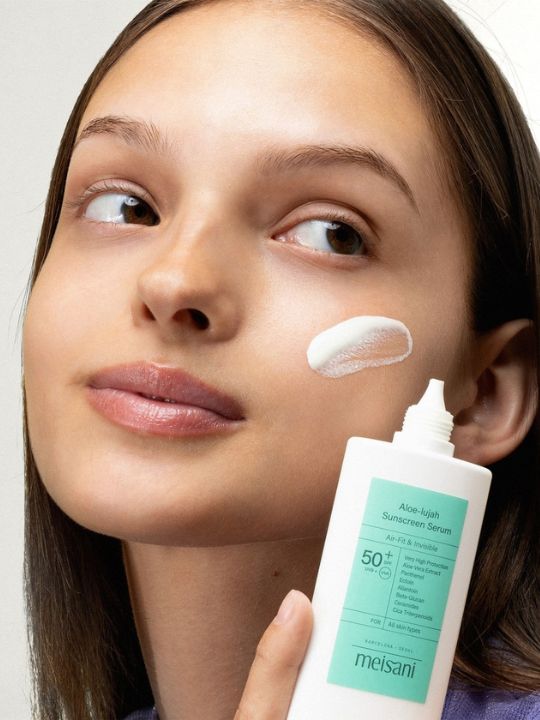 Woman applying Meisani Aloe-lujah Sunscreen Serum to her face.