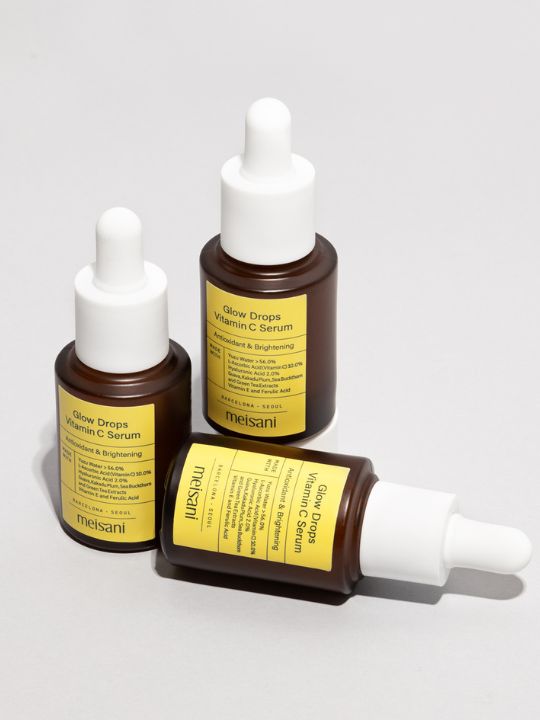 Three bottles of Meisani Glow Drops Vitamin C Serum on a light grey background