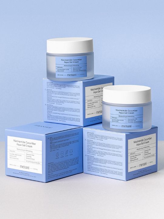 Two jars of Meisani Niacinamide Cucumber Aqua Gel Cream sitting on retail boxes against a light blue background
