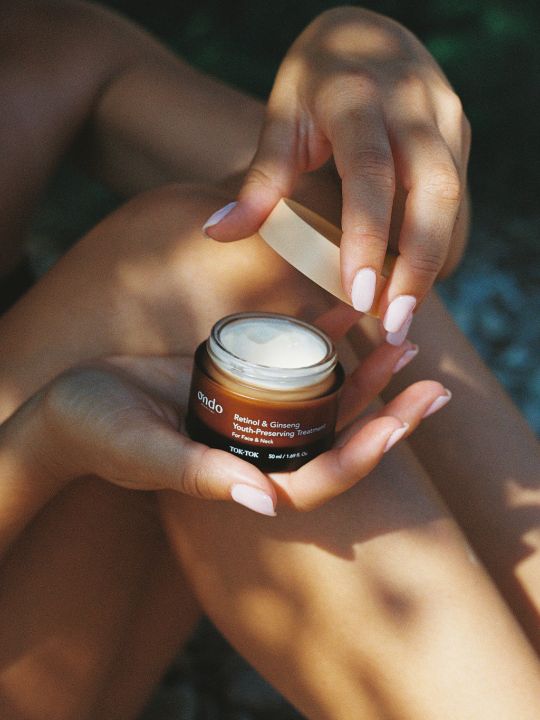 Person holding open jar of ondo beauty retinol & ginseng youth preserving treatment