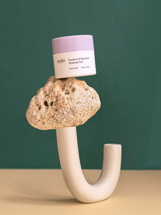 Jar of Ondo Beauty Squalane & Bakuchiol Sleeping Pack on a unique stone holder against a green background