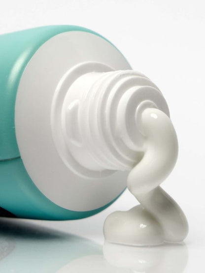 Close-up of Suntique I'm 4 Seasons Hand Suncream with white cream being squeezed out on a white background