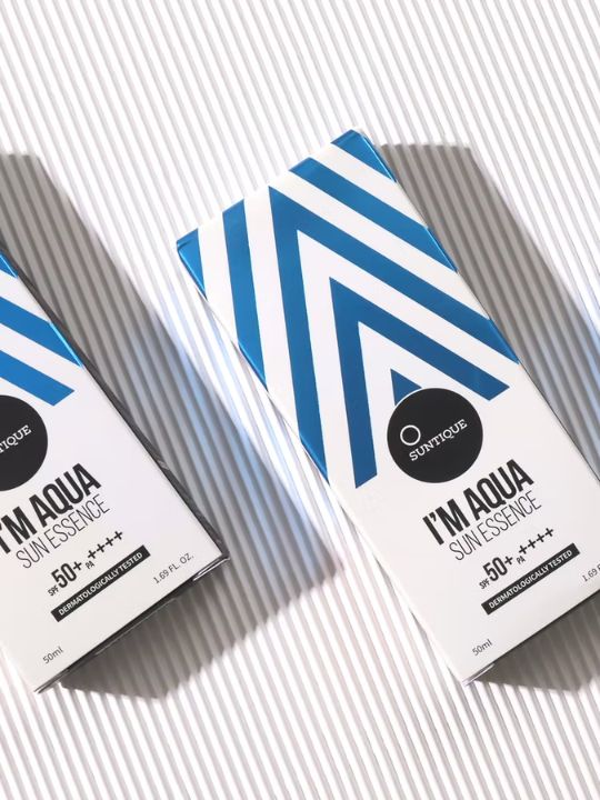 Suntique I'm Aqua Sun Essence boxes on a striped background