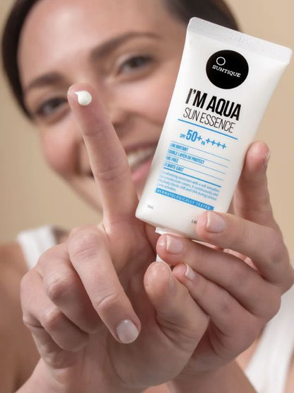 Woman holding tube of Suntique I'm Aqua Sun Essence with cream on her finger
