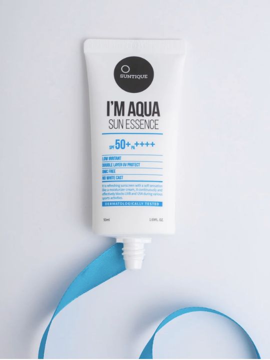 Tube of Suntique I'm Aqua Sun Essence with a blue ribbon on a light grey background