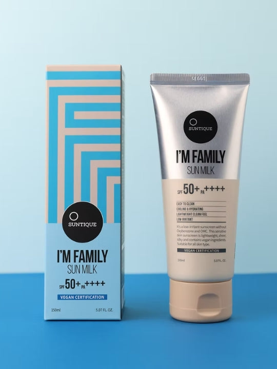 Suntique I'm Family Sun Milk SPF 50+ sunscreen in a silver squeeze tube next to its blue and beige geometric-patterned box, set against a light blue background.