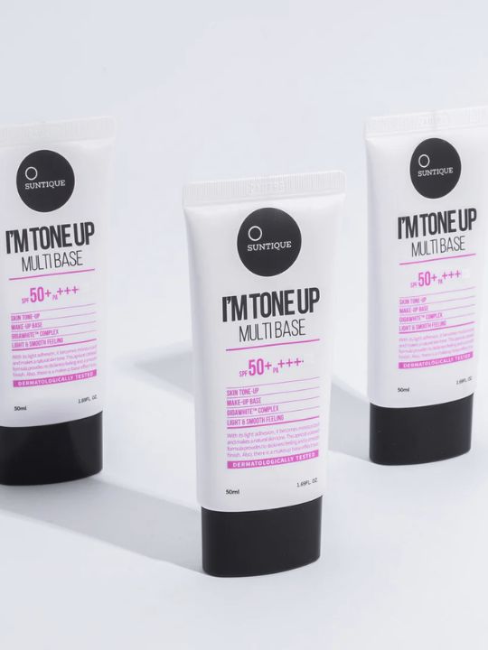 Three tubes of Suntique I'm Tone Up Multibase Sunscreen on a light grey background