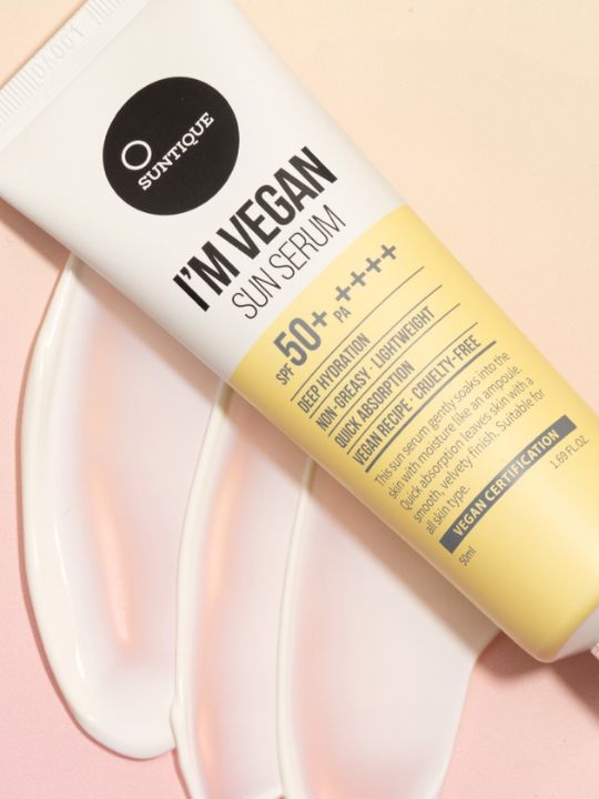 Tube of Suntique Im Vegan Sun Serum with cream swatch on a light pink background.