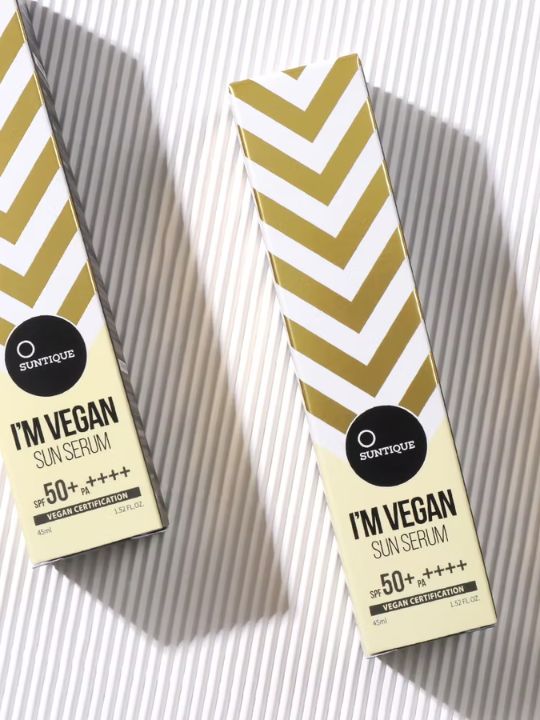 Two boxes of Suntique I'm Vegan Sun Serum on a striped background.