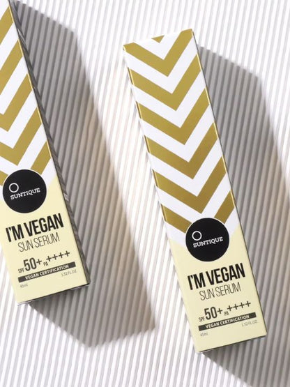 Two boxes of Suntique I'm Vegan Sun Serum on a striped background.