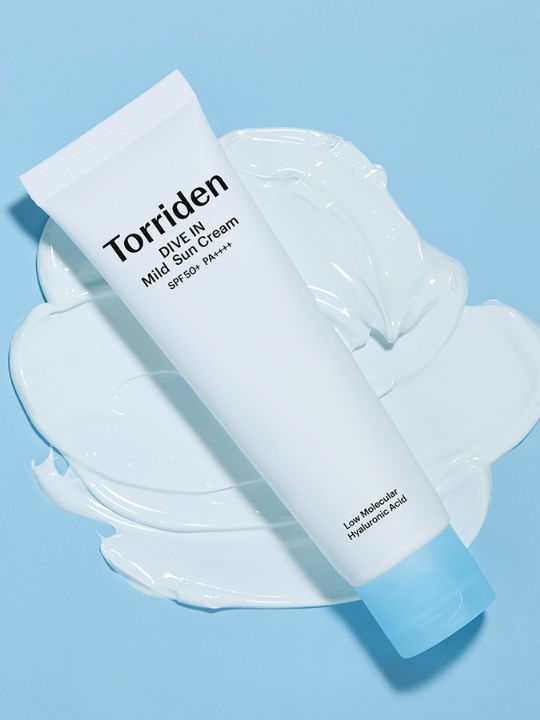 Tube of Torriden Dive In Mild Sun Cream on a large swatch of cream against a light blue background