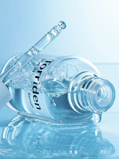 Torriden Dive In Low Molecular Hyaluronic Acid Serum lying on a reflective blue, wet surface with dropper out.