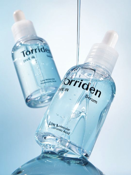 Two bottles of Torriden Dive In Serum  with light blue liquid running down, on a light blue gradient background