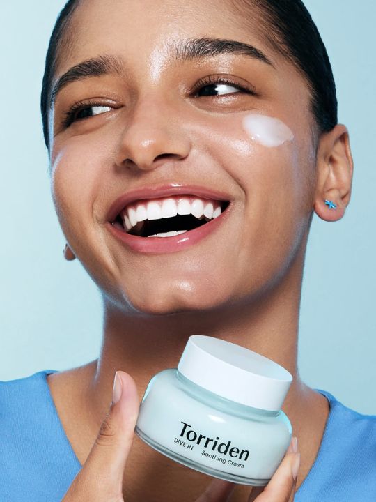 Woman holding a jar of Torriden Dive In Soothing Cream against a light blue background