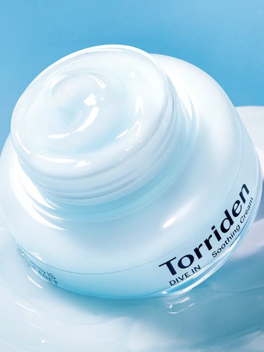Open jar of Torriden Dive In Soothing Cream on a creamy white surface and blue background