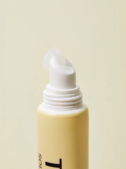 Close up of Torriden Solid In Lip Essence  with cream coming from the opening on a yellow background