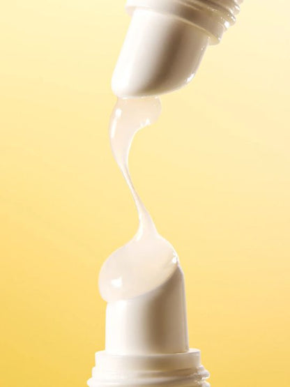 Cream being squeezed out of a tube from above onto another tube against a yellow background