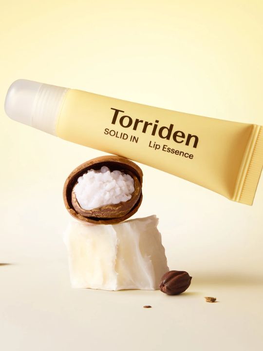 Torriden Solid in Lip Essence balancing on  a cracked nut on a light background