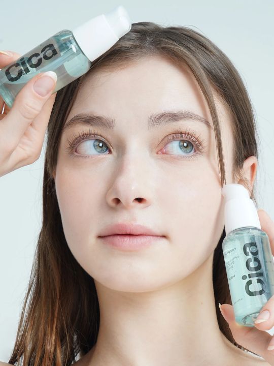 Woman holding two bottles of Vegreen's Fragrance-Free Cica Serum to her face