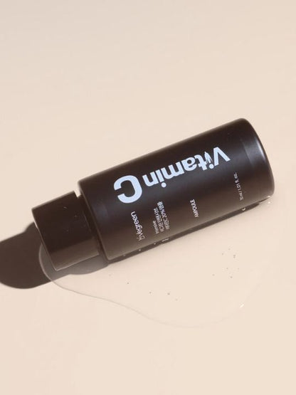 Vegreen Intensive Vitamin C Ampoule lying on a puddle of liquid against a beige background