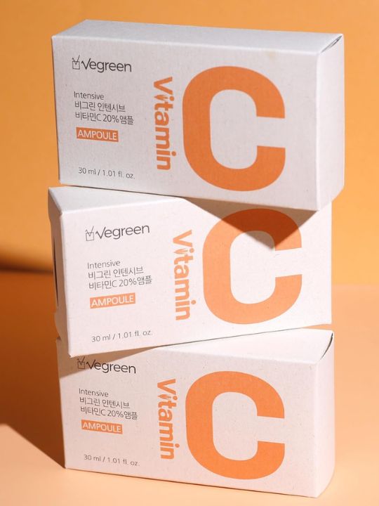 Three retail boxes of Vegreen Intensive Vitamin C Ampoule stacked against an orange background