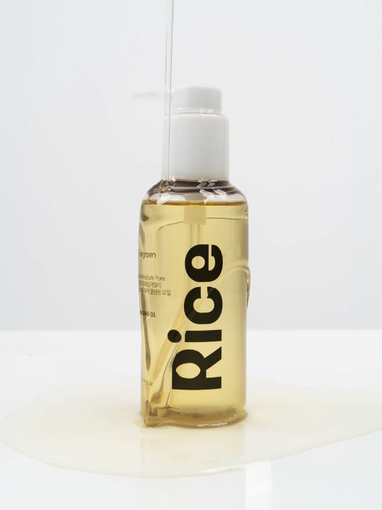 Pump bottle of Vegreen Rice Daily Moisture Pore Cleansing Oil with liquid running down it on a neutral background
